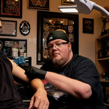 Photograph of tattoo artist Jerry Martin II working on a bicep tattoo at Sacred Mandala Studio in Durham, NC.