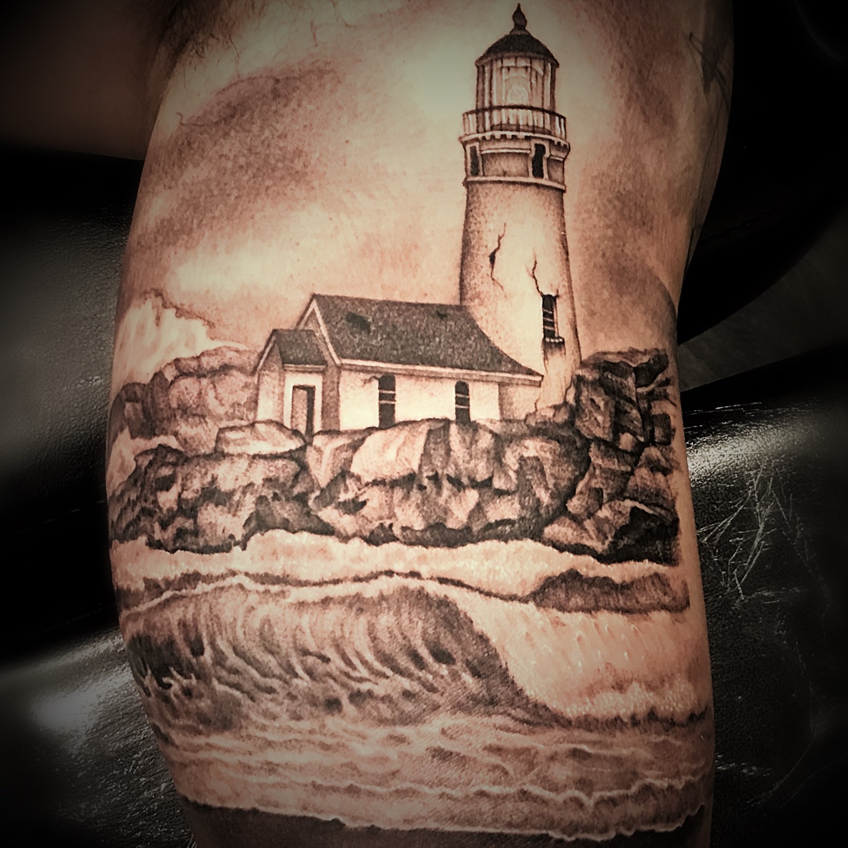 Costal Lighthouse with waves on the rocks - fine line black and grey tattoo created by tattoo artist Alan Lott, Co-founder and tattoo artist at Sacred Mandala Studio in Durham, North Carolina